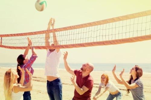 Mensen in gewone kleding die volleybal spelen op het strand