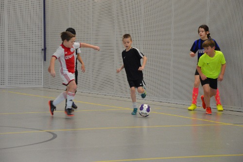 Deelnemers van het oudejaarszaalvoetbaltoernooi 2019 zijn tegen elkaar aan het voetballen